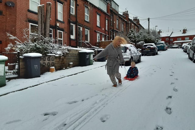 A woman pulls a child along on a sledge in the snow in Burley, Leeds.
