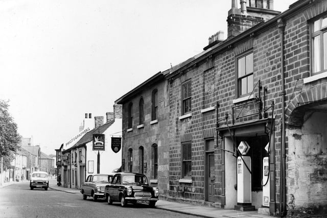 North Street looking north in July 1962. The white building seen centrally is the Swan and Talbot Public House at 34 North Street a posting house, one of two principal inns in Wetherby, the other being the Angel. In a census for 1776 these two inns employed 25 servants servicing the coaching and carrying trades on the busy Great North Road. A daily carrier service operated between Wetherby and Leeds from the Swan and Talbot. Dalby's Garage, in the foreground, has two petrol pumps. It also ran the local ambulance service at the time of this image (1960s). The proprietor lived in the house next door, to the left of the petrol pumps.