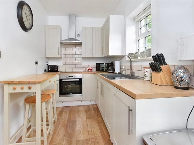 The contemporary kitchen has an integrated oven, hob, dishwasher, and has a rear door directly onto the back access lane.