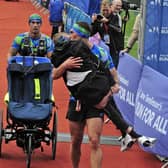 Rob Burrow gets a kiss from his friend Kevin Sinfield as the two cross the finish line of the Leeds Marathon together