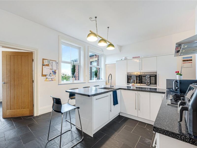 Large windows give the kitchen clear views across the garden, while the breakfast bar provides a practical workspace and casual dining area.