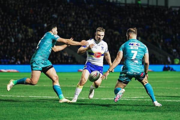 Warrington's George Williams kicks past Rhyse Martin and Aidan Sezer during his side's home win over Leeds in February. Picture by Alex Whitehead/SWpix.com.