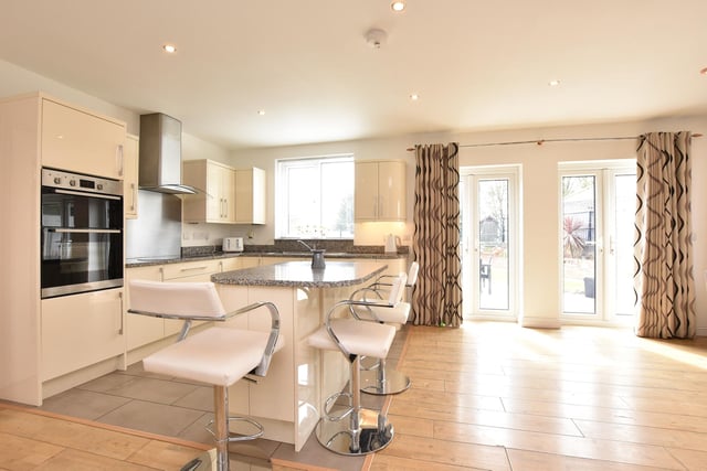 The kitchen area has a range of fitted wall and base units with complementary work surface and integrated appliances. There is a kitchen island with complementary work surface, plus laminate flooring throughout.