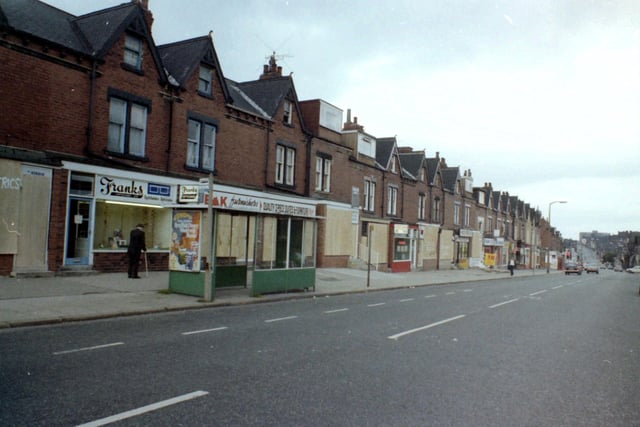 July 1981 and in focus is Harehills Lane showing a parade of shops between Berkeley Road and Strathmore Drive, boarded up for protection as a result of riots which had taken place in the vicinity. Some shops have managed to remain open though, including Frank's Opticians at no. 247 towards the left.
