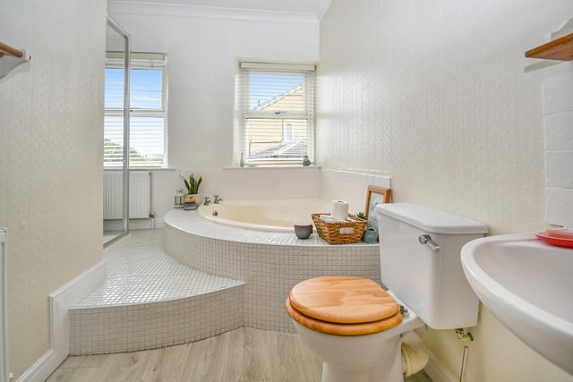 The bathroom has a feature corner bath, step-in shower cubicle, pedestal wash-hand basin and low level WC.