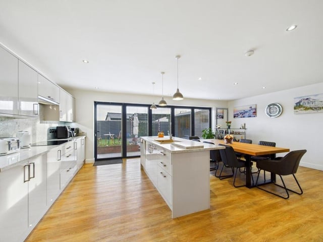 The kitchen diner has a range of wall and base units in a high gloss design with quartz work surfaces over, and is complimented with a matching kitchen island.
