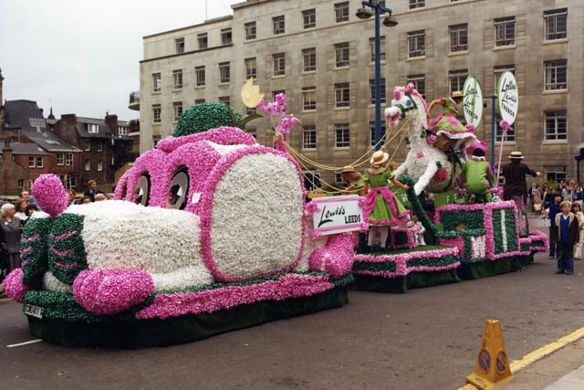 A brightly decorated float by Lewis's department store in association with Trebor. It was one of 70 floats which paraded through the streets of Leeds on the occasion of the 6th Annual Lord Mayor's Parade in June 1979. The procession was over one mile long and included eight marching bands and 400 drum majorettes. 50,000 people turned out to watch. The theme for the parade was 'Together with Children'. Lewis's chose to design this large dog and rocking horse which was cleverly decorated with over 30,000 pink, white and green ribbon bows. The Lewis's girls on the float are dressed in lime green dresses trimmed with shocking pink sashes and frills topped off by straw hats. They handed out lollipops along the route and when they arrived in front of the Civic Hall they saluted the Lord Mayor, Coun Christine Thomas, making sure that she received a lolly also.