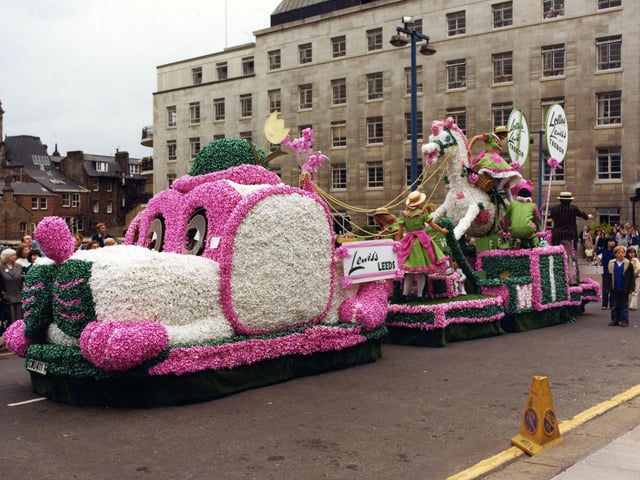 A brightly decorated float by Lewis's department store in association with Trebor. It was one of 70 floats which paraded through the streets of Leeds on the occasion of the 6th Annual Lord Mayor's Parade in June 1979. The procession was over one mile long and included eight marching bands and 400 drum majorettes. 50,000 people turned out to watch. The theme for the parade was 'Together with Children'. Lewis's chose to design this large dog and rocking horse which was cleverly decorated with over 30,000 pink, white and green ribbon bows. The Lewis's girls on the float are dressed in lime green dresses trimmed with shocking pink sashes and frills topped off by straw hats. They handed out lollipops along the route and when they arrived in front of the Civic Hall they saluted the Lord Mayor, Coun Christine Thomas, making sure that she received a lolly also.
