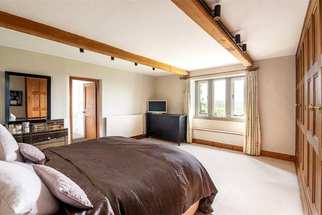 The master suite features exposed ceiling beams and enjoys open countryside views towards Harewood House.