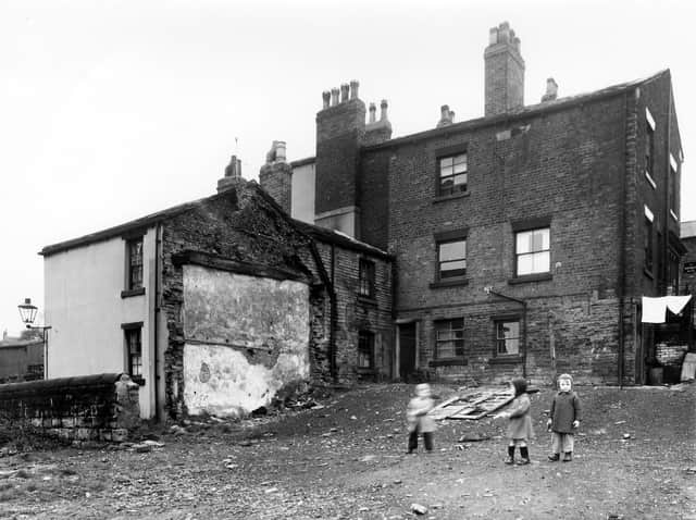 Three small children play with guns on Lower Wortley Road in 1958. These buildings were set for demolition as part of slum clearance plans.