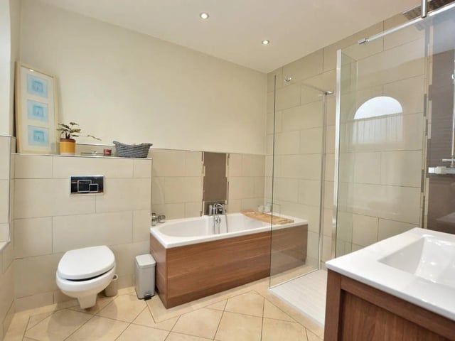 The family bathroom is part-tiled and fitted with a modern white suite including a large walk-in shower enclosure, separate bath, washbasin and WC.