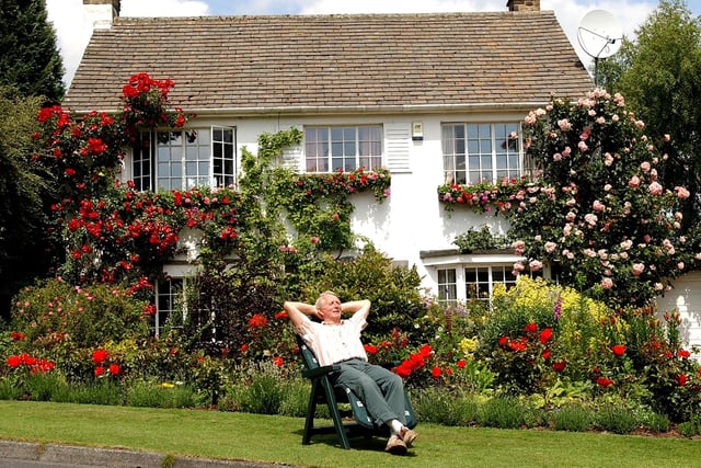 Harold Woodworth relaxes in front of his rose covered cottage on Southway in June 2003.