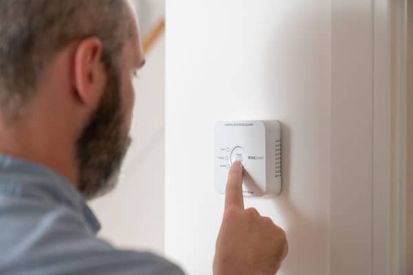 Man checking carbon monoxide alarm
