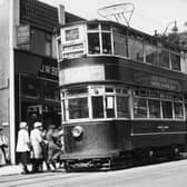 A view showing Chamberlain tram no.110, on route 2 to Moortown, stopping to pick up passengers on Harrogate Road. To the left of the photo is no.51 Harrogate Road, which is home to J.W. Bennett radio and the Leeds and Holbeck Building Society, by the junction with Club Row. To the right is Stainbeck Corner, the junction with Stainbeck Lane, with the edge of the Yorkshire Penny Bank just seen on the far right. Pictured in June 1951.