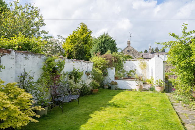 This lawned garden lies to the rear with a seating area and mature trees and shrubs.
