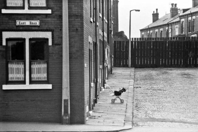 Easy Road in 1969. A baby in a pushchair is on the pavement outside one of the red brick terraced homes. This is perhaps May Grove. Behind the fencing is the railway line that ran from Waterloo Pit at Temple Newsam to the coal staith (Waterloo Main Colliery Depot) at the junction of Easy Road and Cross Green Lane. The 'Paddy train' transported coal from the colliery to the depot where the coal merchants would then distribute it to local households. The train also transported the colliery workers to and from the pit at the beginning and end of their shift.