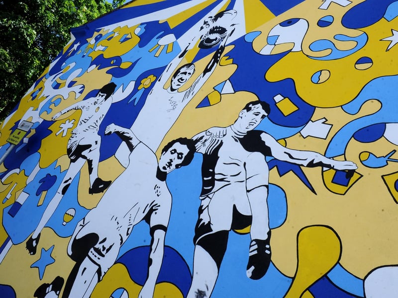 The artwork was created as a tribute to four Leeds United legends following their recent deaths - Jack Charlton, Norman Hunter, Trevor Cherry and Peter Lorimer. It was designed by Nicolas Dixon and the 33ft mural is painted on the side of the Avanta Care building, which overlooks Pudsey Market.