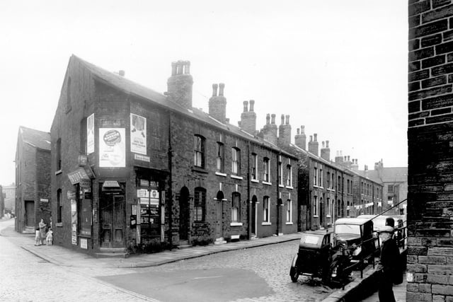 Buslingthorpe Lane is on the left, looking towards the junction with Sheepscar Street/Scott Hall Road. A group of women and children can be seen at the corner of Laycock Street. At the corner with Husler Street is a grocers shop, business of Israel Landy. Pictured in July 1958.