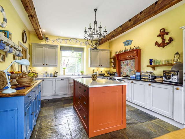 The bespoke breakfast kitchen has a central island and integrated appliances, with a Belfast sink and slate tiled flooring which extends into the utility.