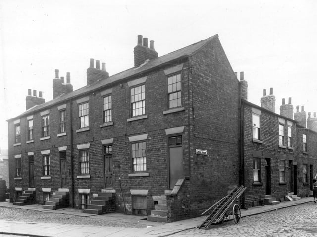 On the left of this view are four houses which are part of Cobden's Buildings. Both odd and even numbers are in view and numbers run from 3 to 6, left to right. Houses have steps down to basement entrances. Louisa Street follows to the right where numbers 12 and 10 are visible. A barrow containing ladders can be seen in the centre which are likely to belong to a window cleaner. Pictured in April 1959.