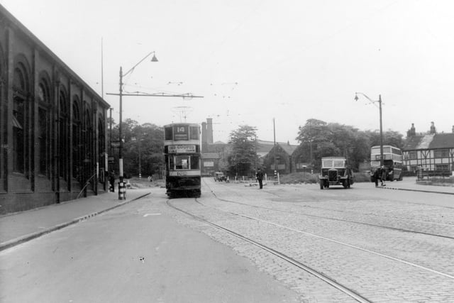 Julky 1940 and in view is Stanningley Road looking towards Town End roundabout, showing number 14 tram with tramway depot to left of picture. A bus, lorry and a van and several people are also shown. In the background are mills, mill chimneys, Bramley National School, Good Shepherd School, trees and half timbered buildings.