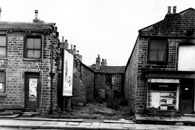 Town Street in September 1963. Number 19 is on the left of the image with posters advertising a visiting circus displayed on the door. In the centre of the image is a space where number 21 Town Street stood before being cleared. Behind is a yard and number 23 Town Street a through by light property. An advertising hoarding promoting Moores Luxury loaf now stands on the site of number 21. On the right at number 25 Town Street is a shop selling motor spares and accessories.