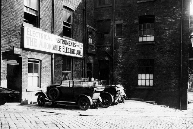 Works building of Electrical Instruments Leeds Ltd, the Automobile Electricians.Stone sets and a sign for Hart service station can be seen and a man leaning on one of the cars. Pictured in August 1927.
