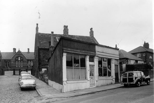 On the left is Upper Wortley Junior and Infants School. On Upper Wortley Road, number 63 is a cafe, to the right number 65 is a sewing machine dealer. This pair of shops has a temporary appearance and have been erected in front of 67, which is the stone building behind. The street on the left is Ashley Road.
