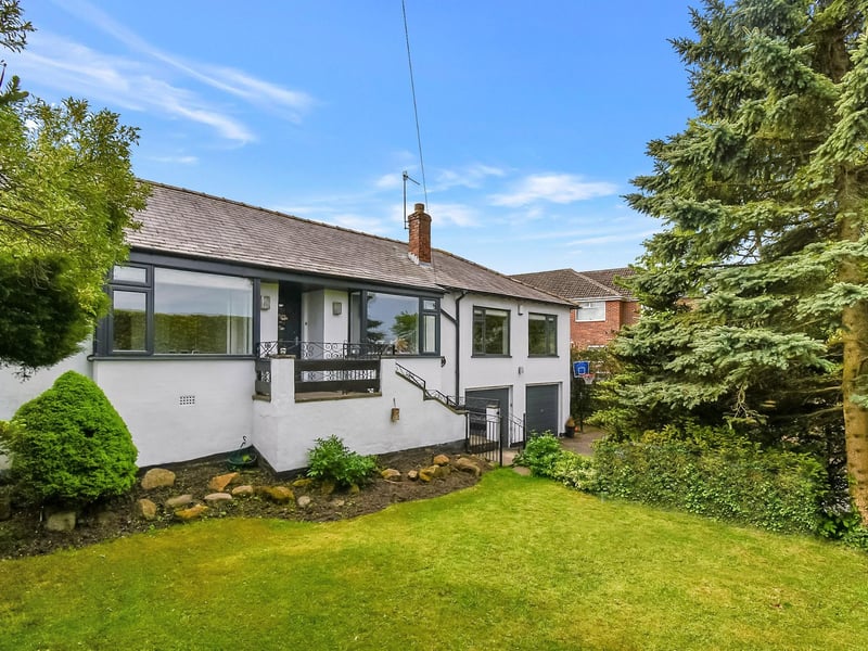 The front garden features a large lawn area with hedged boundaries, ensuring privacy.
