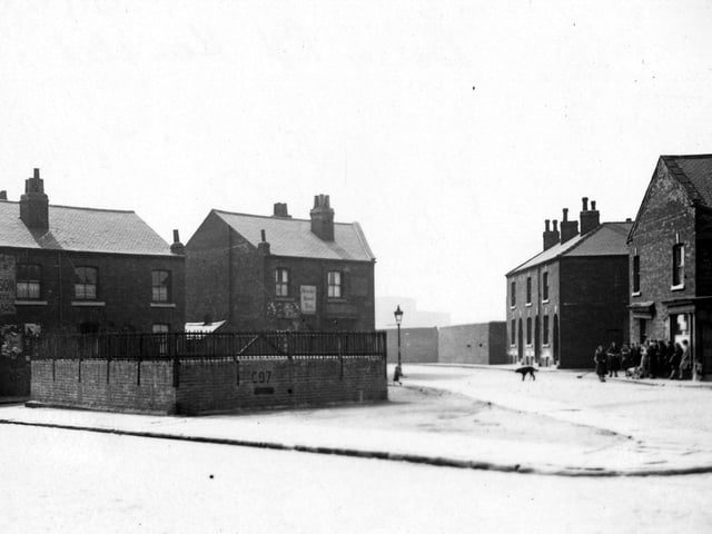 Static water supply tank in Bower Road, at the junction of Grove Road. Shops and houses on Plevna Terrace behind the tank. A group of people are standing on the pavement to the right. Pictured in May 1943.