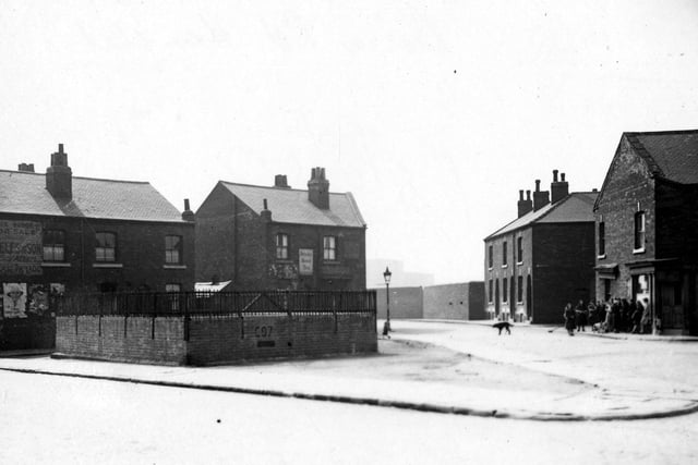 Static water supply tank in Bower Road, at the junction of Grove Road. Shops and houses on Plevna Terrace behind the tank. A group of people are standing on the pavement to the right. Pictured in May 1943.