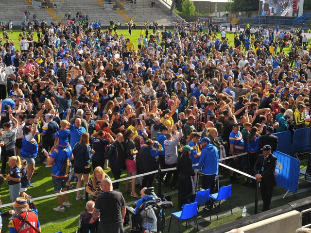 Leeds Rhinos fans party on the pitch after the big win against Bradford Bulls.