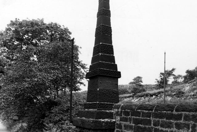 A close-up of pyramid shaped stone milestone set into a wall and shrubs on Abbey Road. A metal plaque on the side says 'To London 200 miles south, to Edinburgh 200 miles north, erected 1829, B & B, Kirkstall forge 1779, Leeds 3 and 3/4 miles'. Pictured in August 1950.