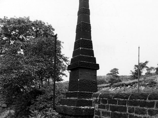 A close-up of pyramid shaped stone milestone set into a wall and shrubs on Abbey Road. A metal plaque on the side says 'To London 200 miles south, to Edinburgh 200 miles north, erected 1829, B & B, Kirkstall forge 1779, Leeds 3 and 3/4 miles'. Pictured in August 1950.