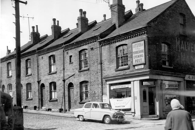 Terraced houses in Brookdale Terrace. The shop is no 1 Malvern Road run by Frank Grant, a newsagents advertising the Yorkshire Evening Post. A lady wearing a headscarf crosses the road towards the shop.