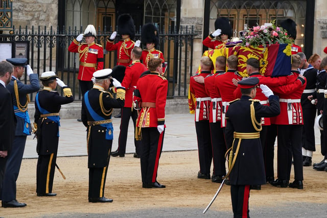 The Prince of Wales, King Charles III and the Princess Royal salute the coffin of Queen Elizabeth II, draped in the Royal Standard with the Imperial State Crown and the Sovereign's orb and sceptre, as it is carried in to Westminster Abbey