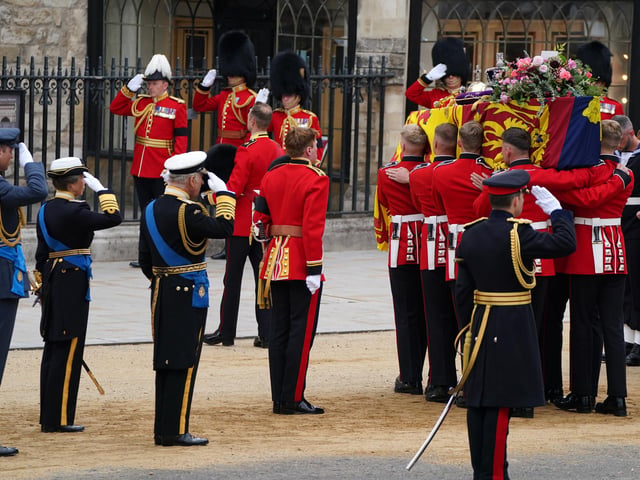The Prince of Wales, King Charles III and the Princess Royal salute the coffin of Queen Elizabeth II, draped in the Royal Standard with the Imperial State Crown and the Sovereign's orb and sceptre, as it is carried in to Westminster Abbey