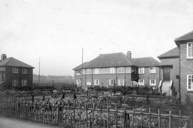 Maisonettes in Throstle Road on the Middleton Estate in September 1932.  At the left edge the flats visible are numbered 97 and 99, but the whole of the property houses numbers 85 to 99. The central block houses flat numbers 101 to 107. On the right-hand side part of a block is seen where flat numbers 109 to 115 can be accessed. There are vegetable plots to the front of the housing, and a playing field to the rear.