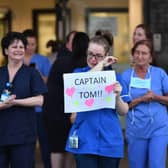 An NHS staff member wipes her eyes as she holds a sign to thank British veteran Captain Sir Tom Moore for his fundraising efforts. (Pic: Getty Images)
