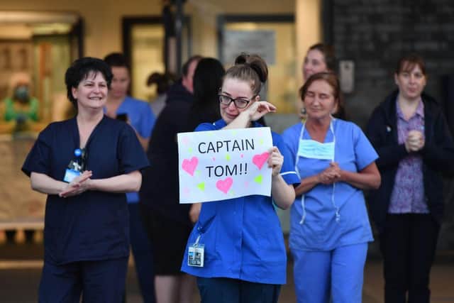 An NHS staff member wipes her eyes as she holds a sign to thank British veteran Captain Sir Tom Moore for his fundraising efforts. (Pic: Getty Images)