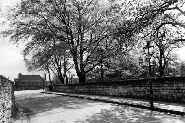 Looking south along Church Lane to junction with Harrogate Road. A streetlamp is prominent in the foreground. A brick wall lines either side of the road. Pictured in May 1957.