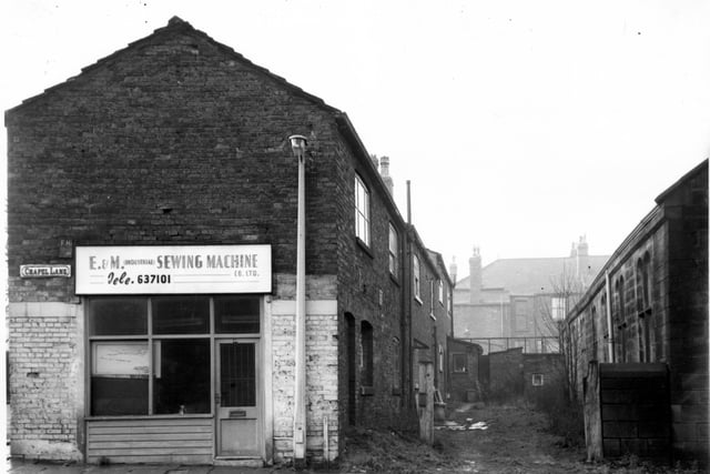 The premises of E and M (Industrial) Sewing Machine Co Ltd, sewing machine engineers and agents. Moving right, the backs of houses on Church Road. Back Wesley Road in the distance then part of Armley Higher Grade School on the right edge. Pictured in  December 1967.