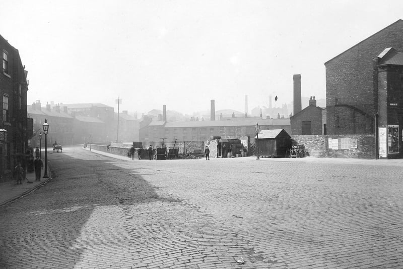 This view looks down Quarry Hill towards the junction with Lady Lane, to the right, and St. Peter's Street, to the left in August 1913. The junction with Templar Street is on the far right edge. In the centre is a wall separating Lady Beck from the road. To the right of the wall in front of railings are handcarts, workmen's huts and tools.