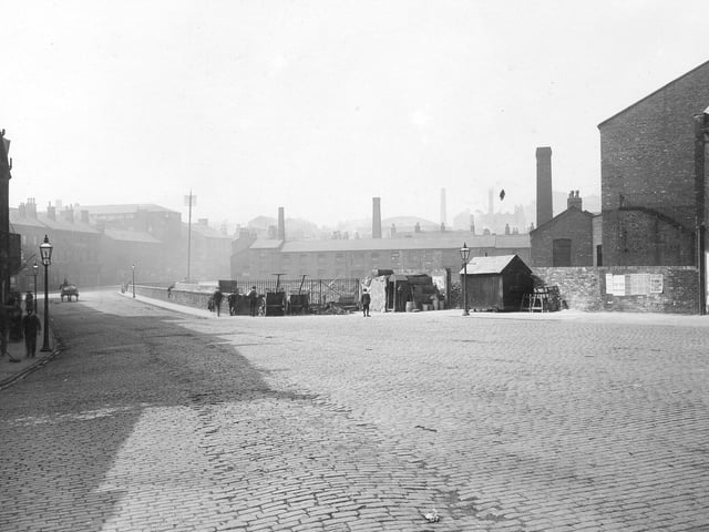 This view looks down Quarry Hill towards the junction with Lady Lane, to the right, and St. Peter's Street, to the left in August 1913. The junction with Templar Street is on the far right edge. In the centre is a wall separating Lady Beck from the road. To the right of the wall in front of railings are handcarts, workmen's huts and tools.