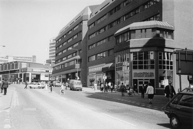A view of Albion Street showing St. John's Shopping Centre which opened in 1985. The Leamington Spa Building Society and National Provincial Building Society are among businesses occupying premises around the outside. On the left, past the junction with Merrion Street, is the Merrion Centre on Woodhouse Lane.