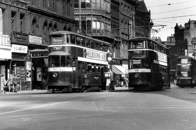 A line of trams on Boar Lane in September 1953. No.527 in front is on route 20 to Halton, while no.545 is on route 15 to Whingate. These are both Feltham trams originating from London. In the background is tram no.275. Shops on the left include Tatler cinema, F.G. Abe & Co., stationers and printers, and Albert Cowling's Wine Lodge.