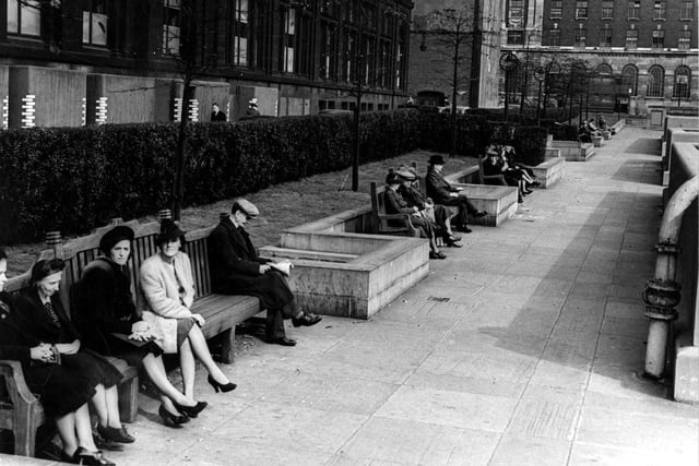 A view looking east along the Garden of Rest between the Headrow and Centenary Street, towards Cookridge Street in September 1943. Members of the public sit on the large benches in front of a hedge. Behind the hedge are the Municipal Buildings (Library, Art Gallery and Police H.Q.). Air raid protection around ground floor of Municipal Building.