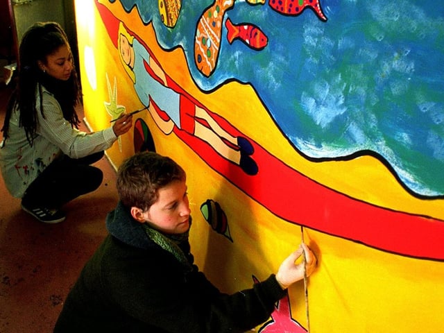 Diana Store, front, of Groundwork Trust and community arts worker Yinka Okpara,  put the finishing touches to a mural at The Dean on Halton Moor which had been designed by children. Pictured in October 1997.