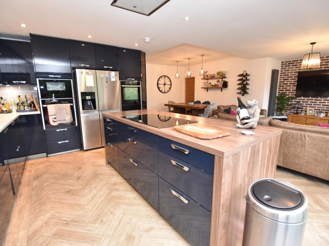 The open plan living/dining kitchen hasa high spec gloss units with quartz worksurfaces, tiled splash backs, two integrated Neff hide and slide ovens, a breakfast bar with induction hob with extractor hood over, integrated Bosch washing machine and dishwasher, Amtico flooring and two bi fold doors to the rear garden.