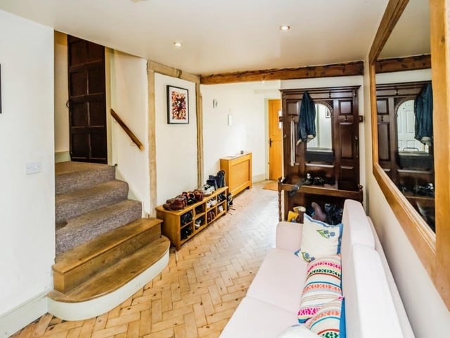 The beamed hallway with parquet flooring has a door that is thought to date back centuries.